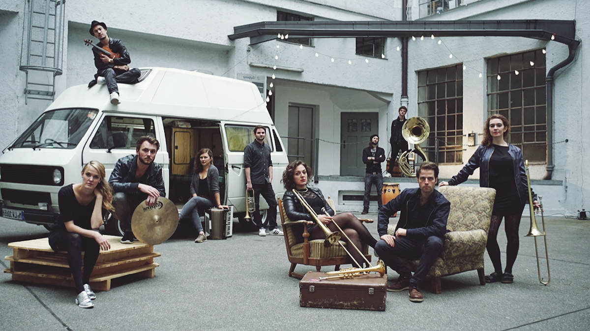 Die zehnköpfige Band Donnerbalkan um ihren Tourbus herum vor dem Münchner Studio