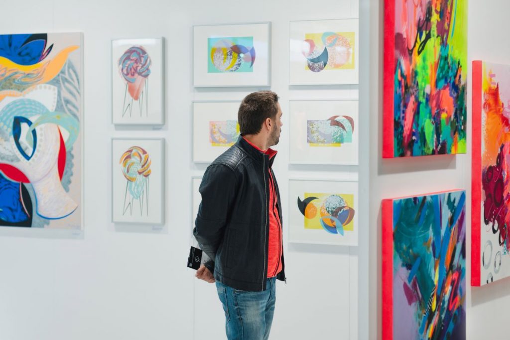 Ein Mann betrachtet Bilder eines Künstlers auf der ARTMUC in München.