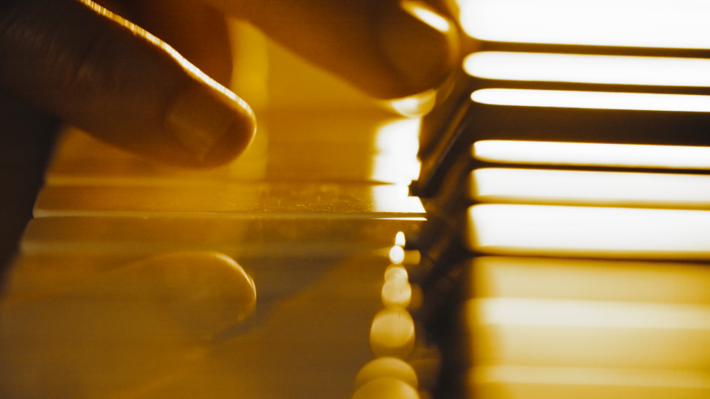 Hier ist eine Bildbeschreibung für das Foto: Nahaufnahme der Hände von Fabian Kratzer beim Klavierspielen. Die Finger berühren sanft die Tasten, während das warme, goldene Licht die Szene stimmungsvoll in Szene setzt. Die Reflexionen auf den glänzenden Tasten verleihen dem Bild eine besondere Tiefe und Ästhetik.